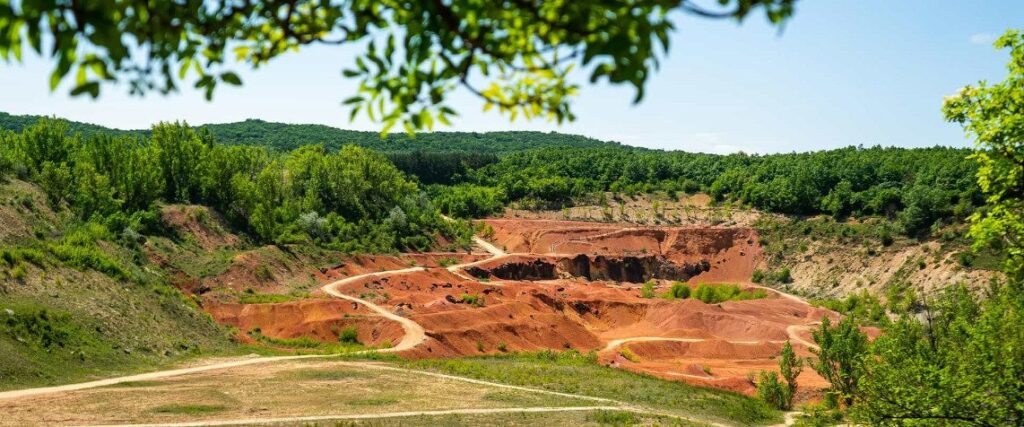 Kép: Távolról, mint egy hatalmas, de már gyógyulóban lévő seb – olyan a tájban a gánti egykor aktívan működő bauxitbánya külszíni fejtési területe.